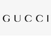 Paveikslėlyje pavaizduotas žodis GUCCI juodomis didžiosiomis raidėmis dideliais tarpais vienspalviame baltame fone. Tai prabangių drabužių prekės ženklo "Gucci" logotipas.